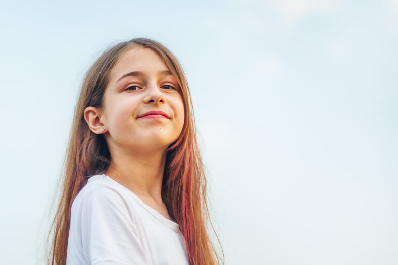 Niña 11 años. Retrato de una adolescente con el pelo largo contra el cielo.