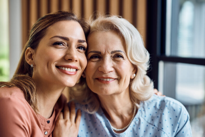 Portrait of happy woman and her senior mother looking at camera.