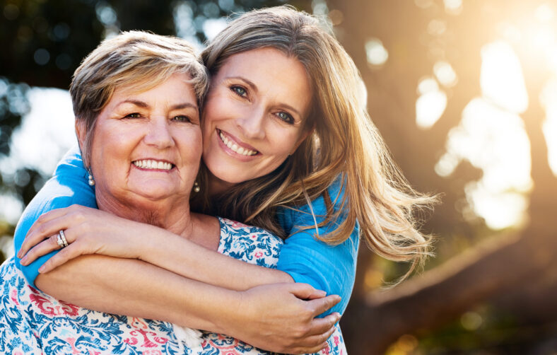 Portrait of a happy mature woman hugging her mother outdoors.