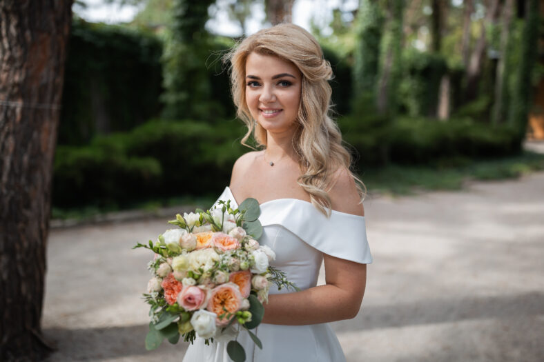 Smiling wedding couple in love in the forest hold hands and hug. Sunny day, good mood. Portrait of a beautiful blonde.