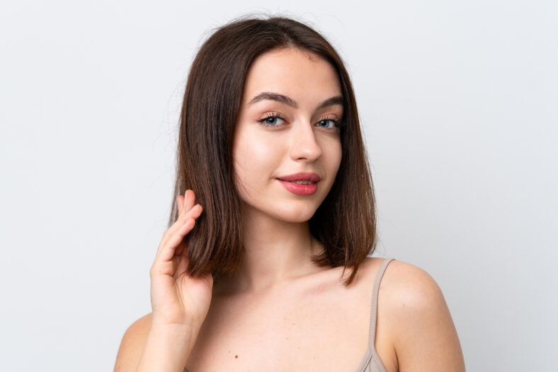 Young Ukrainian woman isolated on white background touching her hair. Close up portrait