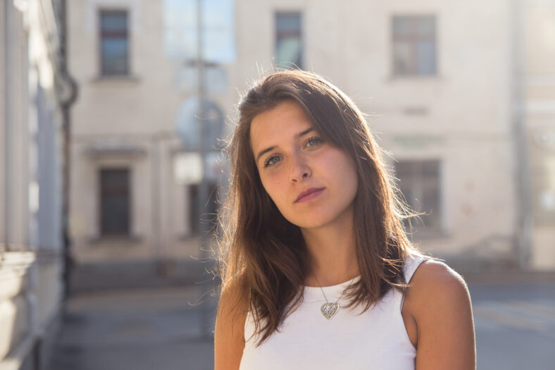Retrato de una linda chica morena en el fondo de una casa de la ciudad en un día soleado de verano