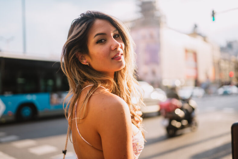 Positive female tourist on street of Madrid city, Spain and shooting on camera, walking in historical places alone, enjoying solo trip.