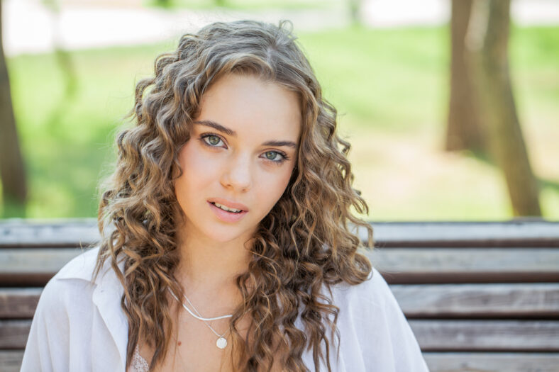 Close up portrait of a young beautiful blonde girl in summer park