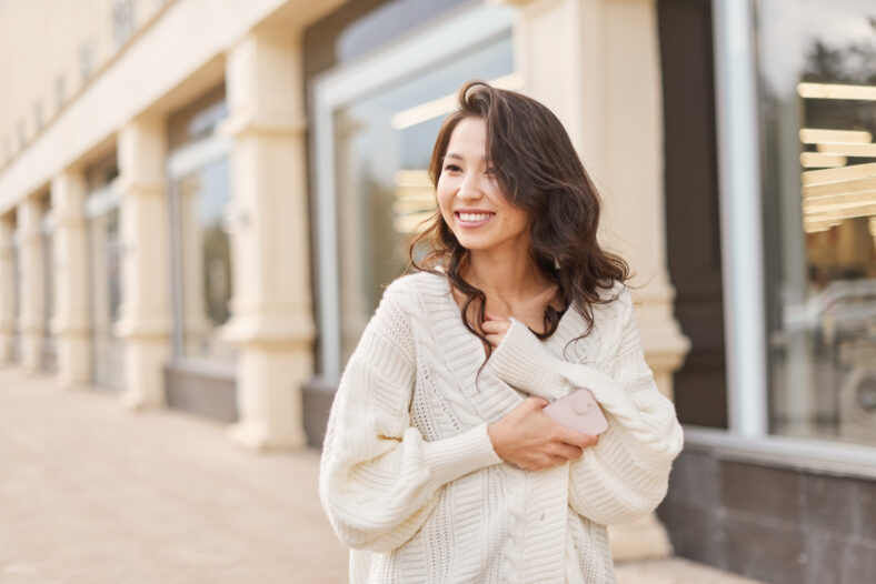 Retrato de estilo de vida de la hermosa mujer asiática Kazajh con una sonrisa de brillo con suéter blanco caminando por la calle en la ciudad de Uralsk. Belleza natural. Cara feliz. Espacio de copia