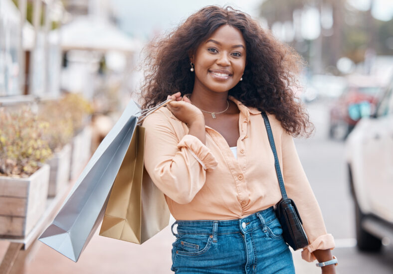 Mujer negra, compras y bolsas con sonrisa en la ciudad en venta, descuento y al aire libre urbano. Retrato de compradores femeninos afroamericanos felices que tienen regalos sonriendo en felicidad para el mercado de la ciudad.