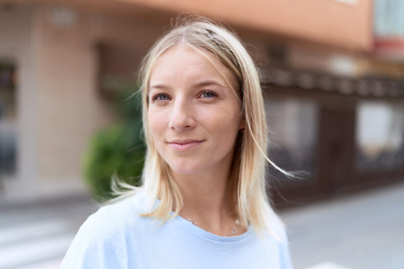 Young blonde woman smiling confident standing at coffee shop terrace