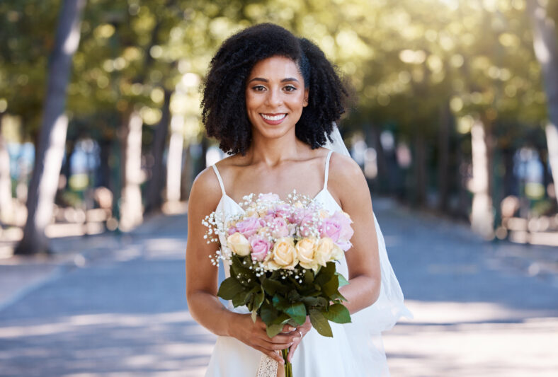 Black woman, wedding and bride portrait with bouquet of roses happy about love celebration. Street, happiness and flowers of a young person smile at marriage commitment event smiling outdoor.