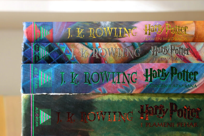 Pila de libros de fantasía por el famoso autor JK Rowling. Estantería en el fondo. Enfoque selectivo.