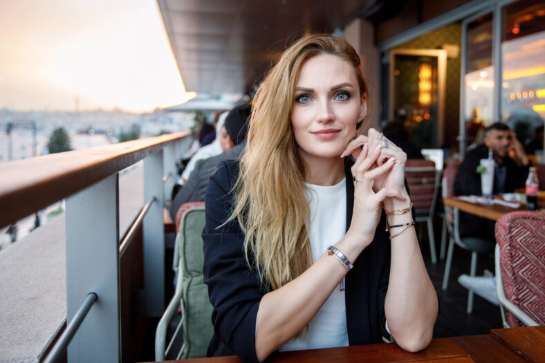 Young business woman drinking cappuccino and cup of coffee. Happy alone woman in outdoor cafe or restaurant on sunny summer day, break for lunch between meetings
