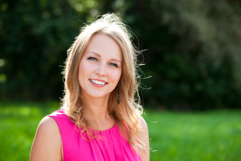 Portrait close up of young beautiful woman, on green background summer nature
