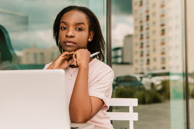 joven afroamericana sentada frente a una computadora portátil