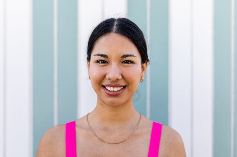 Portrait of happy young ethnic woman with braces in summer clothes standing outdoors. Young people and summertime concept