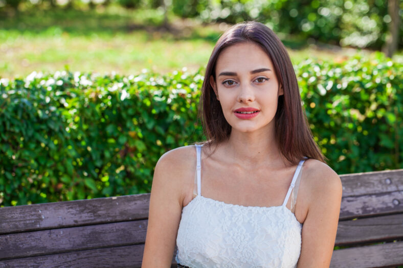 Close up portrait of a young beautiful brunette girl in summer park