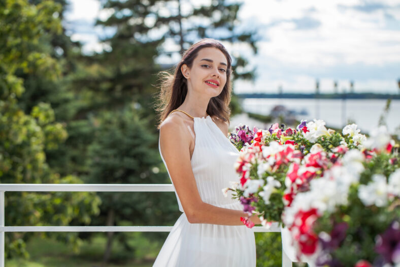 Portrait of a young brunette woman in long white dress