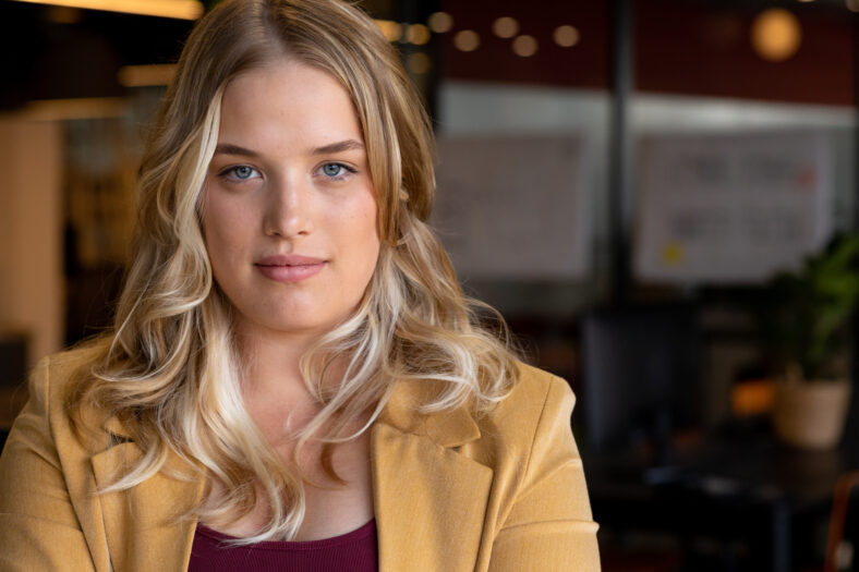 Portrait of happy plus size caucasian casual businesswoman with long blonde hair in office