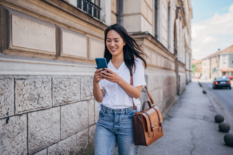 Young Japanese woman reading a message on the mobile phone in the city