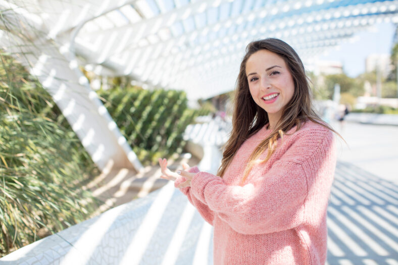 pretty woman feeling happy and cheerful, smiling and welcoming you, inviting you in with a friendly gesture