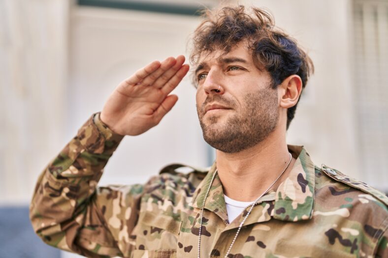 Young man army soldier doing military salute at street
