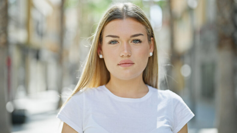 Young blonde woman standing with serious expression at street