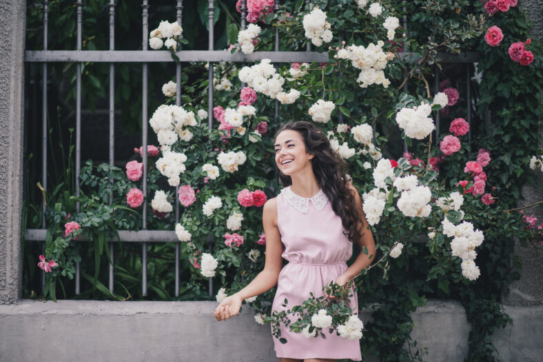 Young woman among roses in a garden