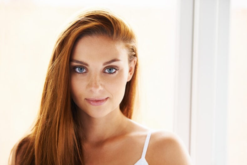 Cuidado del cabello, retrato o mujer feliz por ventana con belleza, cuidado de la piel o resultados para brillo, brillo o colágeno. Sonríe, cara o modelo femenino con cosméticos para el tratamiento, textura saludable o crecimiento en el hogar.