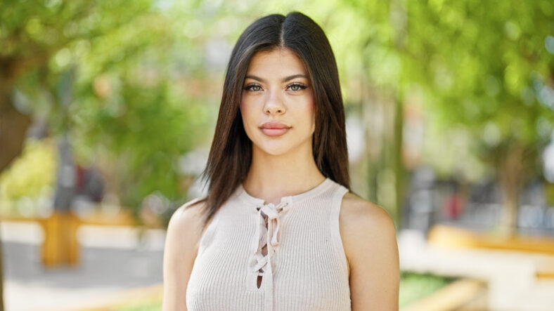 Young caucasian woman standing with serious expression at park