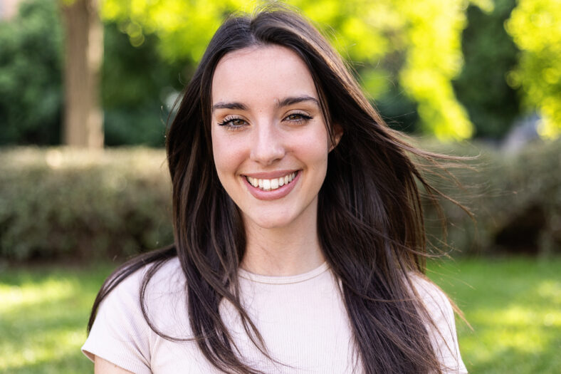 Young beautiful caucasian woman smiling at camera standing outdoors. Portrait of millennial happy girl at city street.