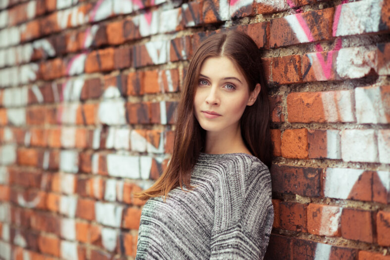 brunette woman portrait in front of a brick wall