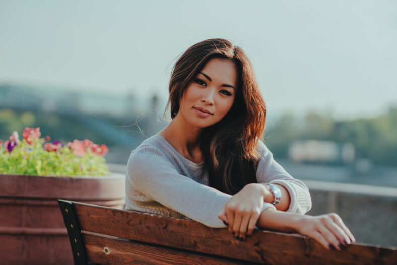Young beautiful woman sitting on bench portrait on summer day