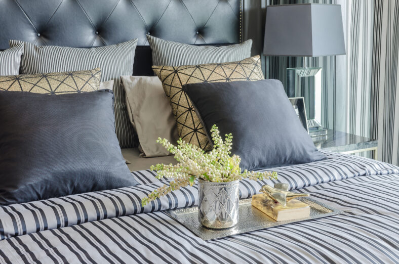 tray of book with vase of plant on bed in luxury black bedroom at home