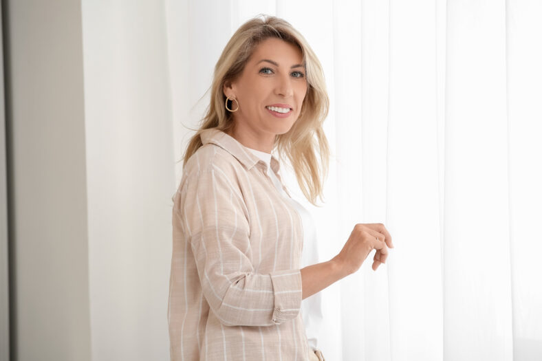 Portrait of beautiful mature happy woman near window at home