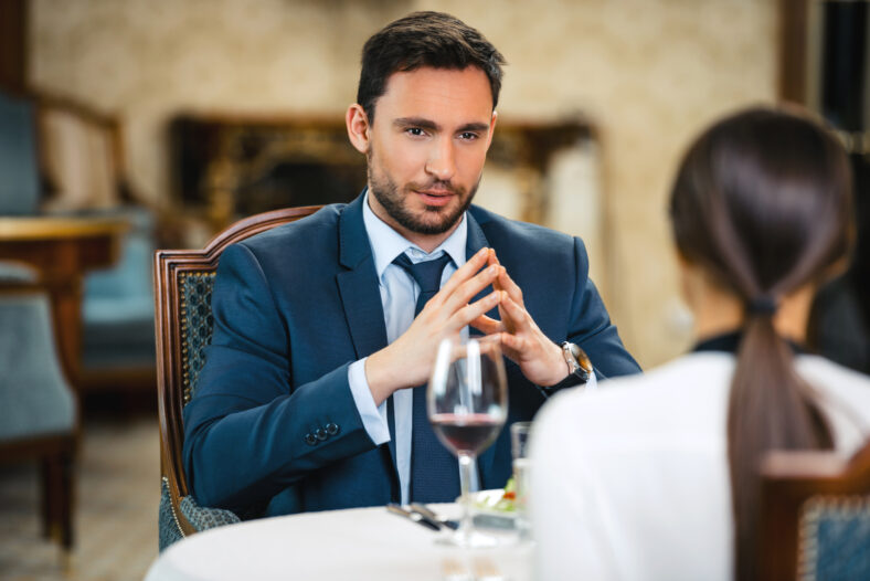 Photo of business meeting in expensive hotel. Young businessman talking with business woman while having dinner