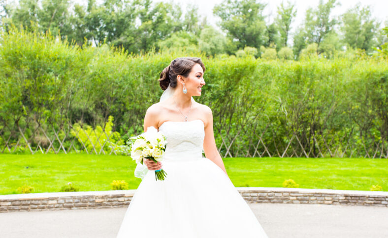 Beautiful bride girl in wedding dress with bouquet of flowers, outdoors portrait.
