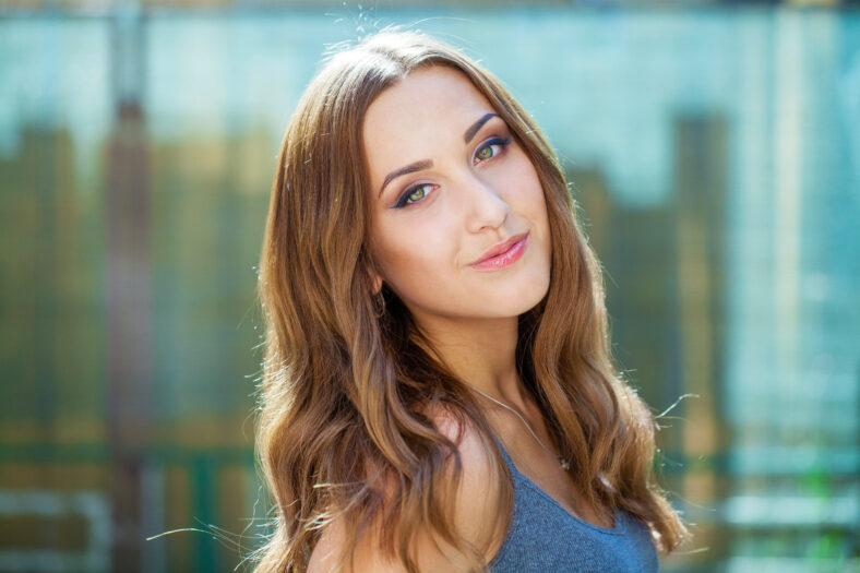 Close up portrait of beautiful young happy brunette woman with fresh and clean skin, summer street outdoors