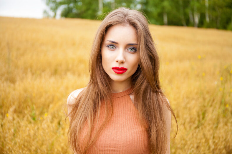 Portrait of a young girl on a background of golden wheat field, summer outdoors