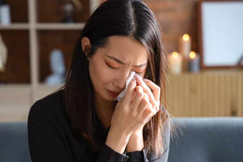 Grieving young Asian woman crying at funeral, closeup