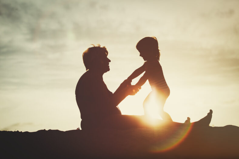 silhouette of grandmother and little granddaughter play at sunset beach