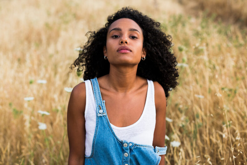 outdoors portrait of a young afro american woman on yellow background