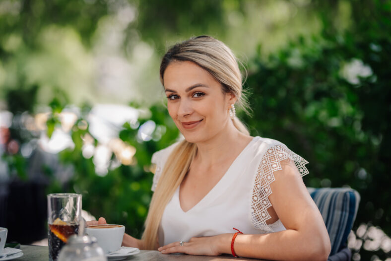 Young businesswoman drinking cappuccino and relaxing at outdoor cafe, enjoying her coffee break
