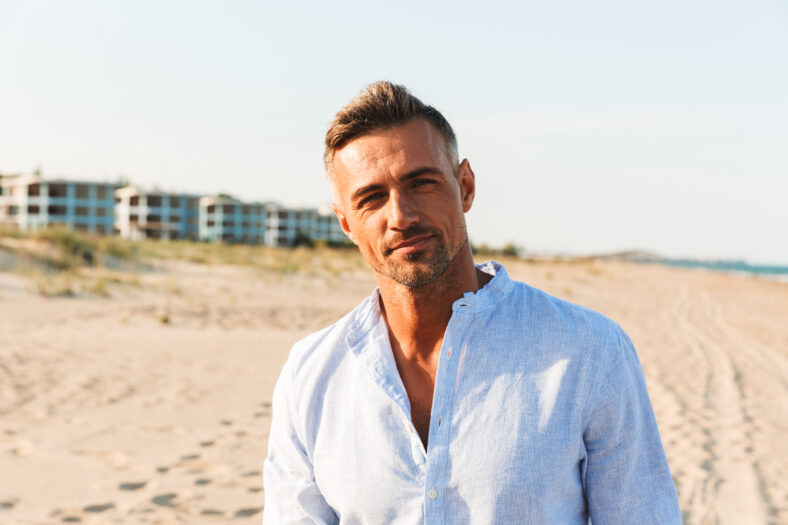 Portrait of a handsome man in shirt standing at the beach