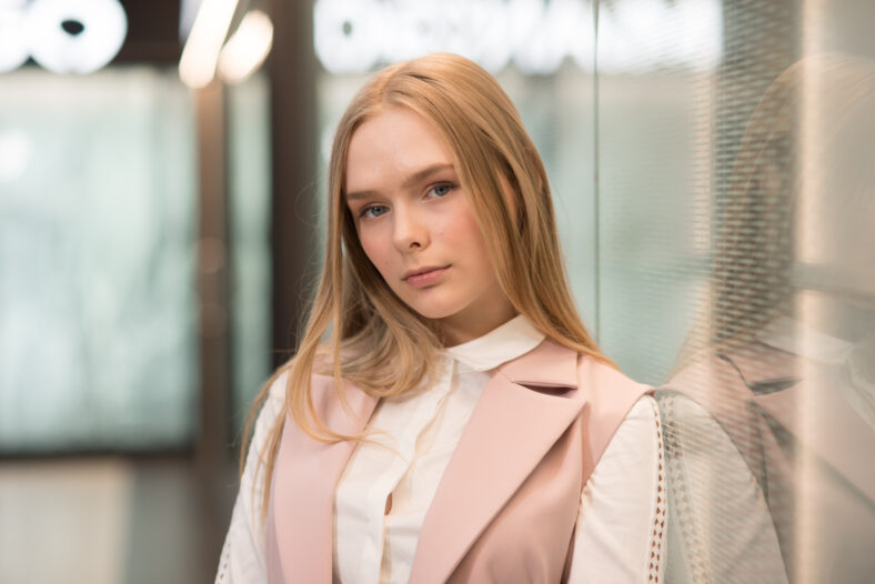 blonde girl in a pink suit posing in a bright room