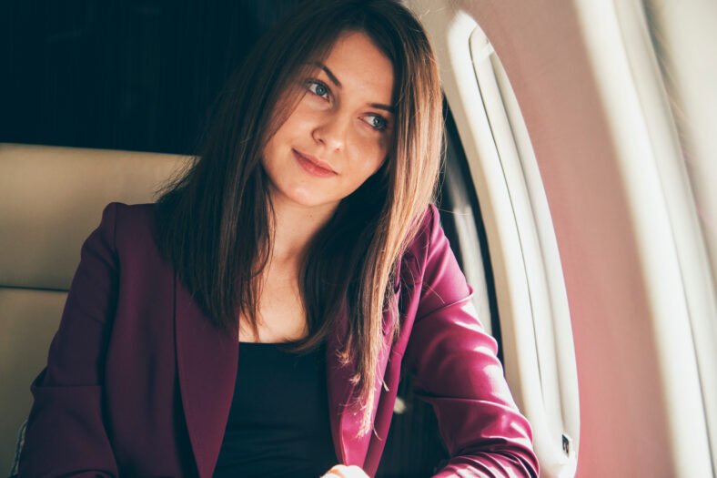 beautiful young woman sits in a plane near the window and look outside at sunny day