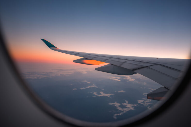 Silhouette wing of an airplane at sunrise view through the window.
