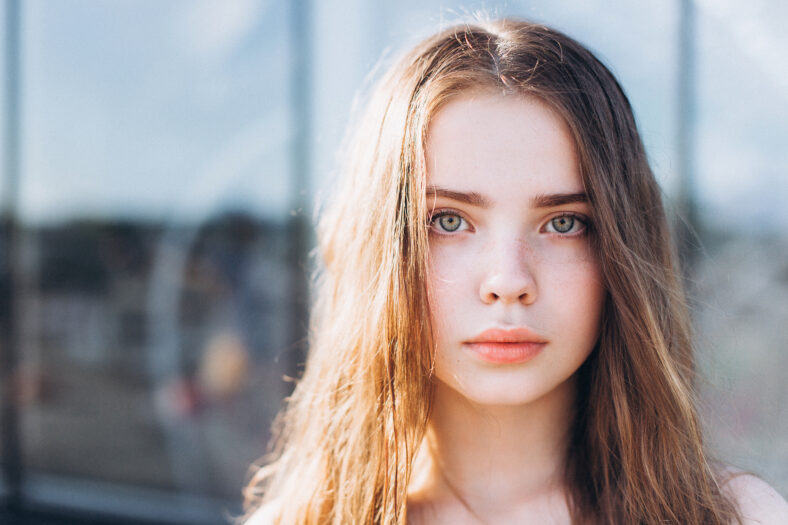 Cute cheerful portrait of young teenage girl outdoors in the street . Emotions, portrait, beauty concept