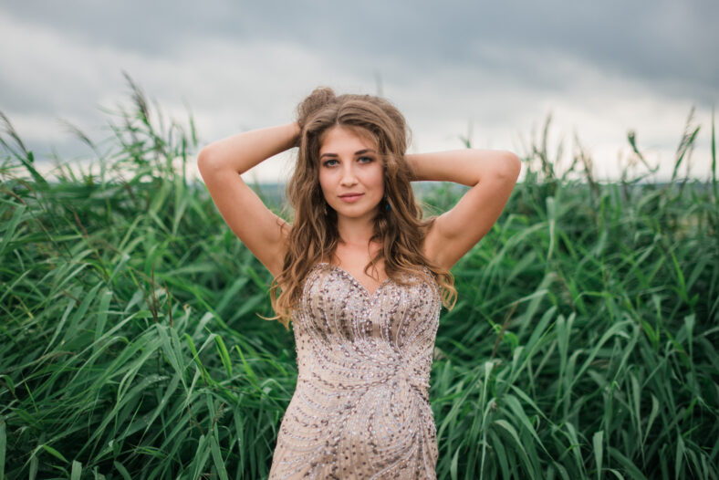 beautiful young girl in a summer dress in a field on a background of green grass