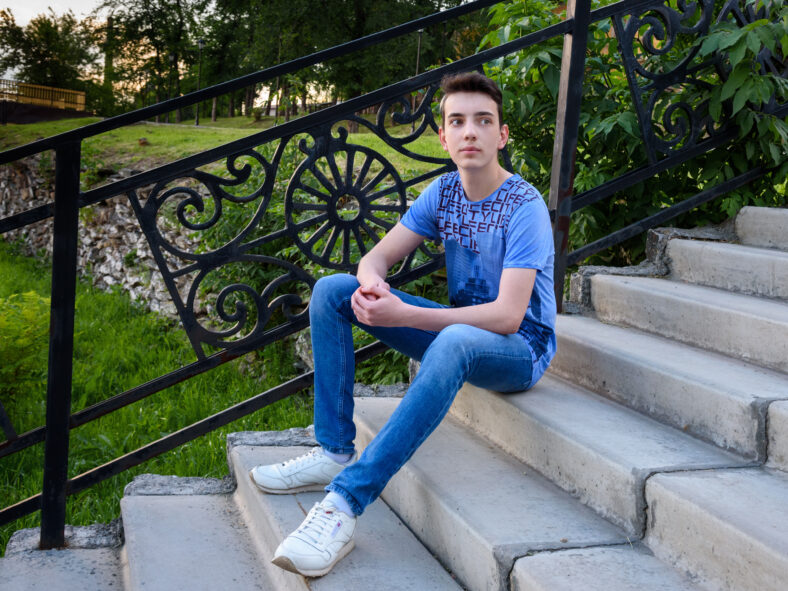 Teenage boy on the stairs on the street in summer