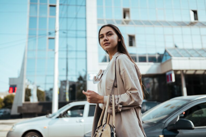 Young busy business woman with long dark hair in a white blouse walks around the city for a meeting