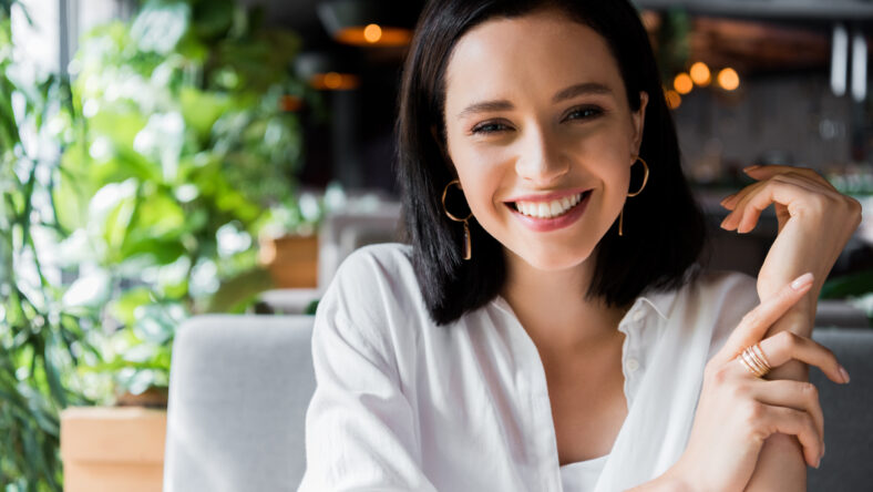 positive young woman looking at camera in restaurant
