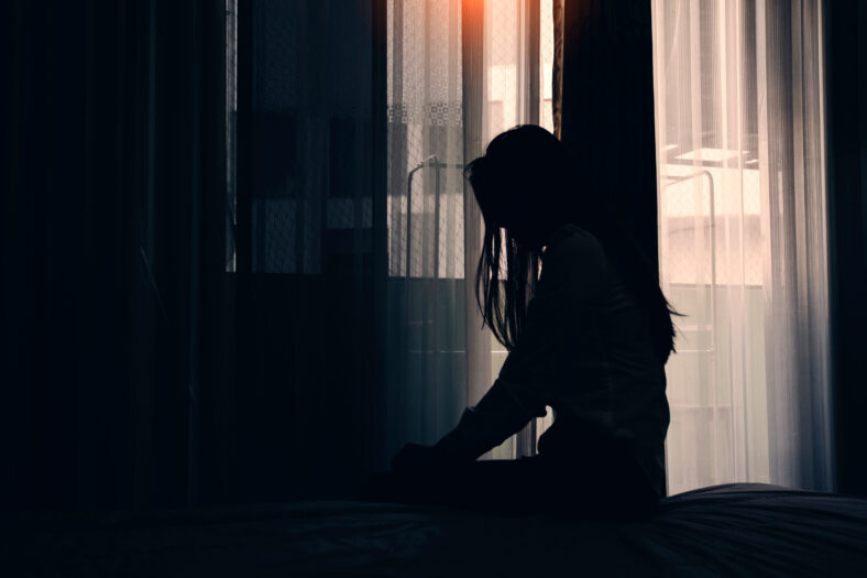 Sad young woman sitting on the bed in the bedroom, People with depression concept.